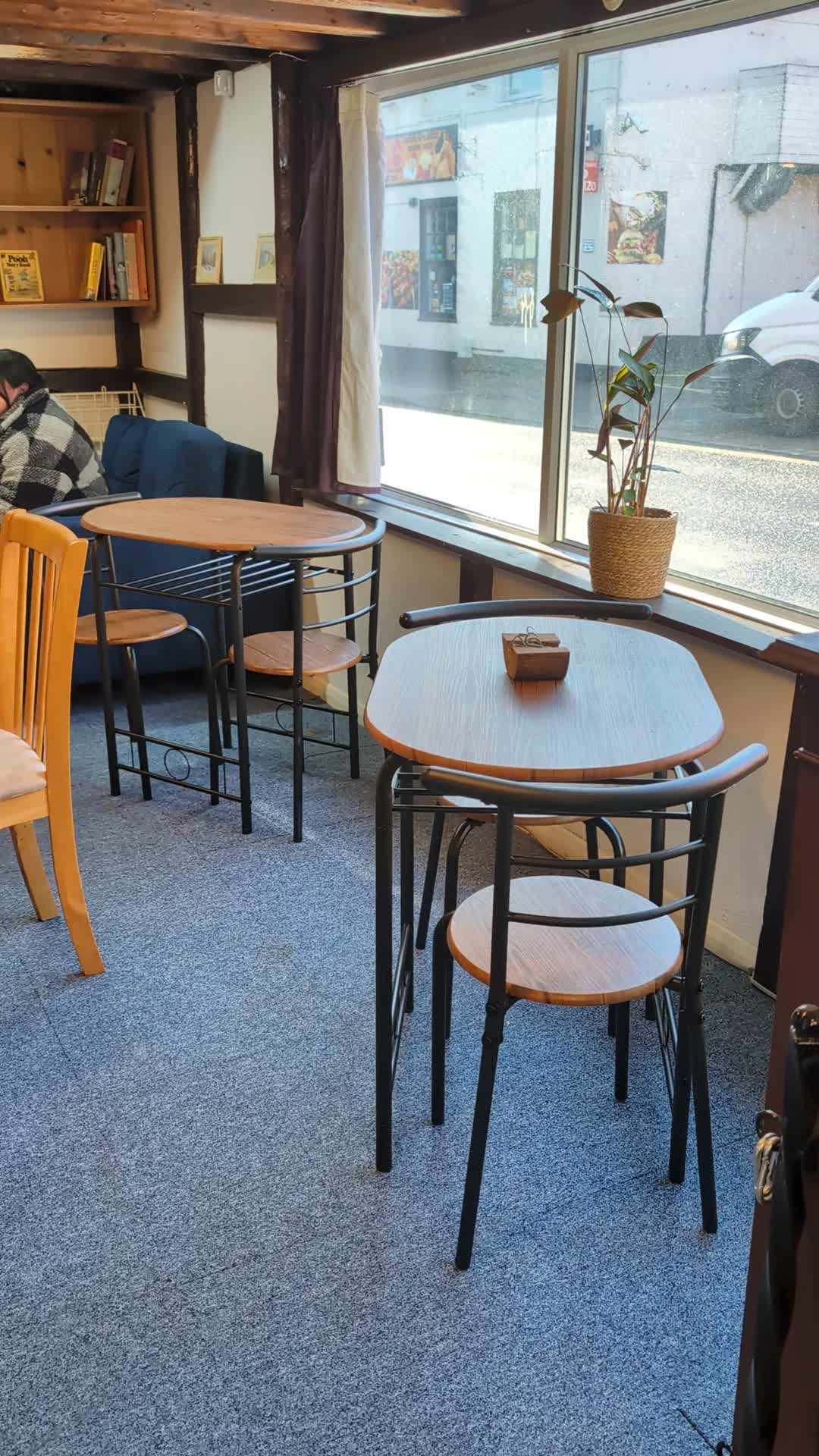 Tables and chairs on blue carpet beside Project40Seven’s windows overlooking the High Street